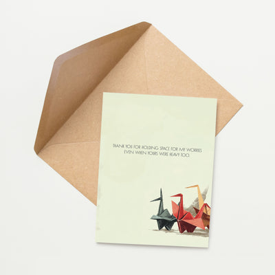 Card with origami cranes and text on a light green background with a brown envelope.